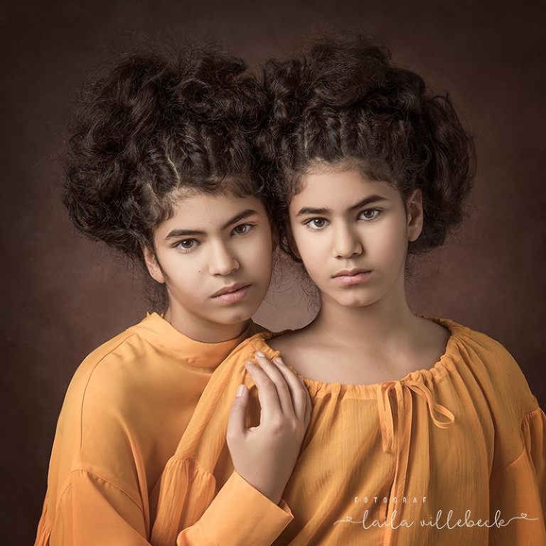Porträtt på tvillingar i senapsgula blusar på brun fotobakgrund