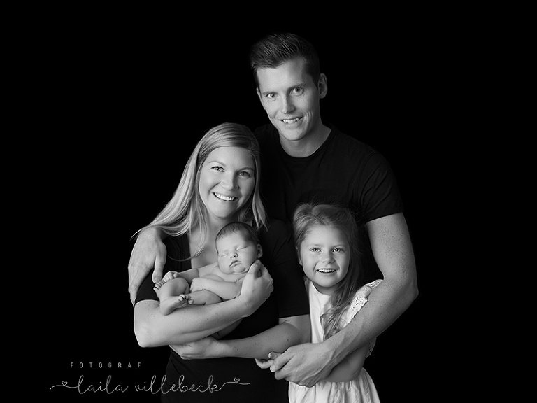 Familj med två barn i svartvitt på svart bakgrund