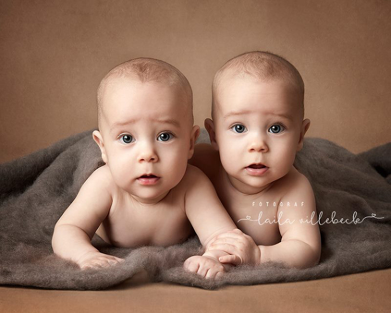 Tvillingpojkar ligger på en ullfilt och kramas