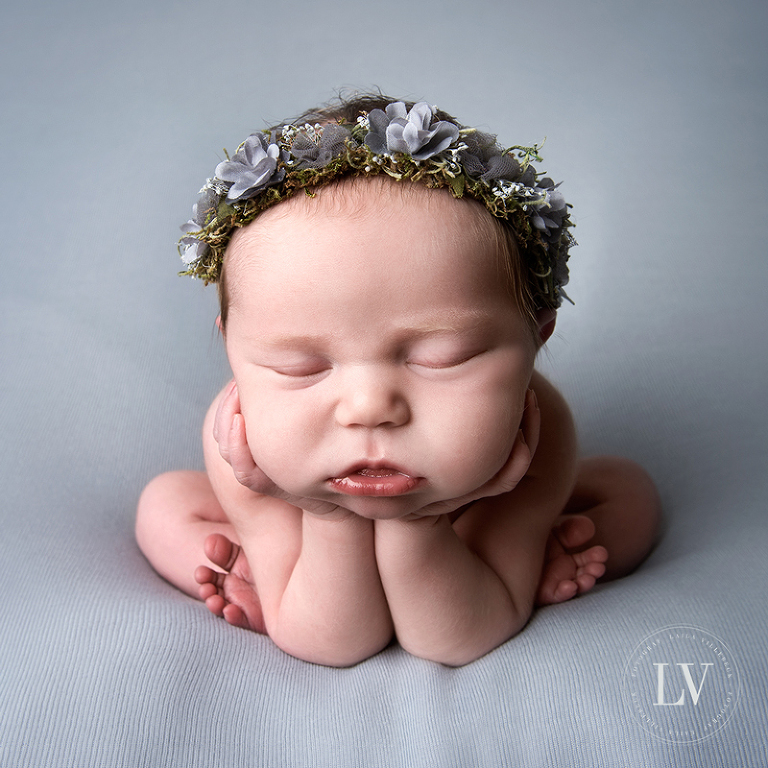 Söt liten nyfödd tjej i froggy pose med grått hårband