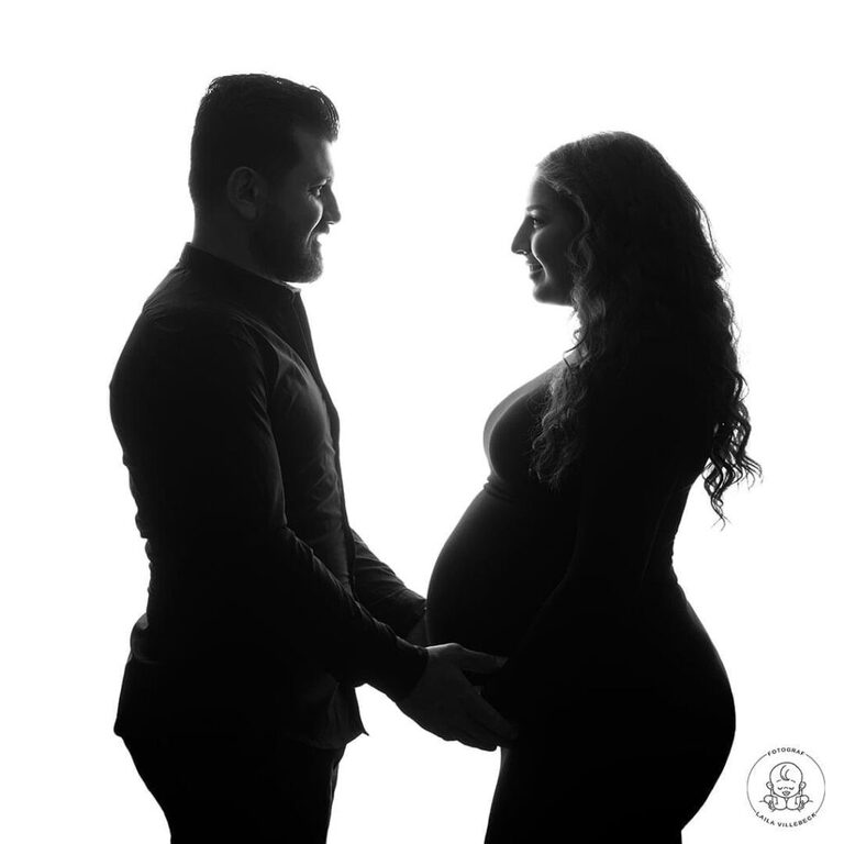 Siluettbild från en gravidfotografering i Linköping med blivanda mamma och pappa står mittemot varandra, i profil mot kameran