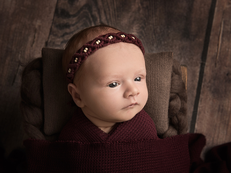 Vaken nyfödd i vacker rekvisita i vinrött för nyföddfotografering