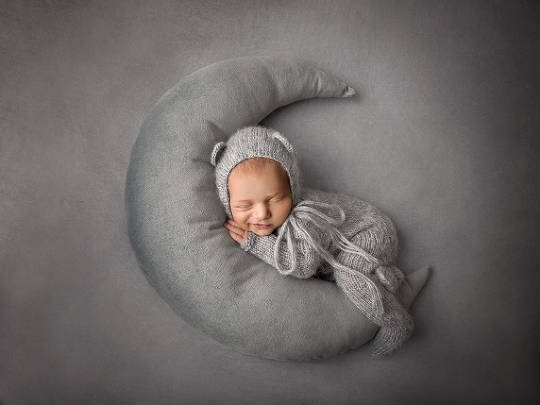 Nyfödda Ossian ligger med ett snett leende på en grå måne