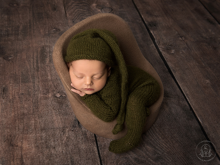Mossgrönt i kombination med brunt blir väldigt fint på nyföddbilder. Här har bebisen en stickad mörkgrön outfit med en matchande stickad sovmössa. Min lilla fåtölj för nyfödda har fått ett brunt överdrag och underlaget är ett brunt trägolv. Naturnära känsla.