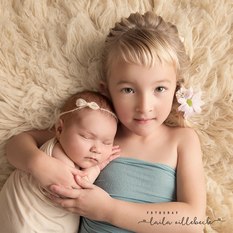 På en cremefärgad fäll ligger Majken och håller stolt nyfödda Ida som sover på hennes arm
