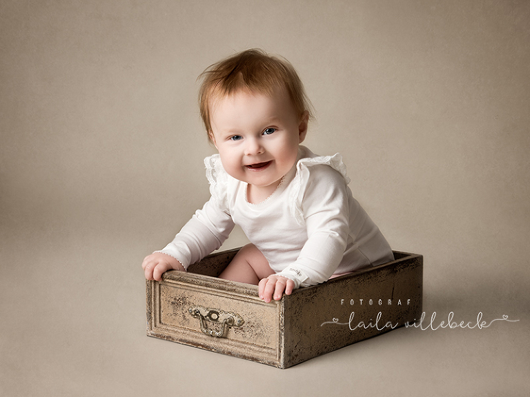 6 månaders bebis sitter i en låda och skrattar.