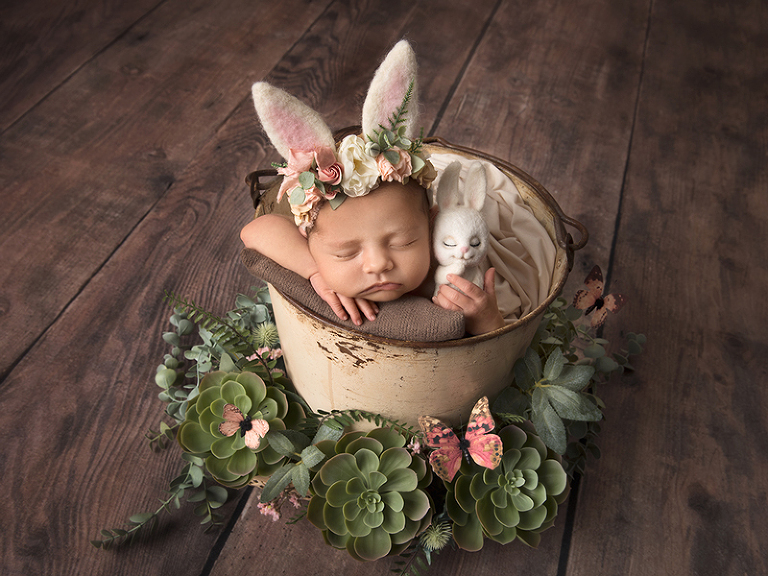 Nyfödd flicka i hink med kaninmössa