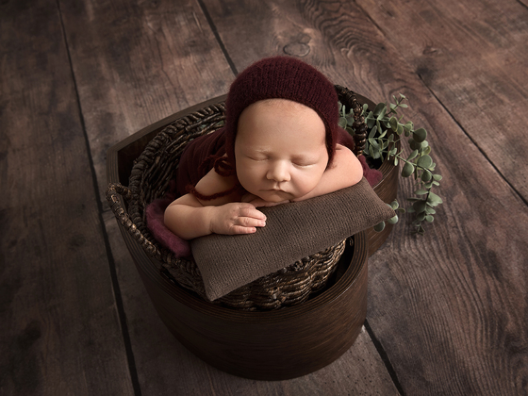 Poserad nyfödd i en korg med hjärtform under en nyföddfotografering