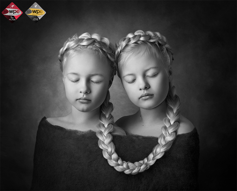 De blonda tvillingarna Märta och Saga sitter ihop med en fläta. Bilden vann barnkategorin i WPE Awards Children First Half 2021
