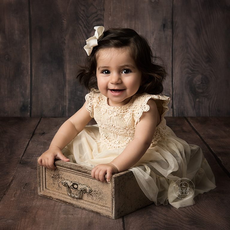 En glad liten bebis som sitter i en byrålåda.