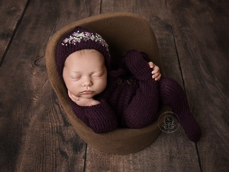 Nyföddfotografering med Elsa från Boxholm. Här har hon på sig en stickad outfit i lila från Dreaming Carita med en matchande mössa med brodyr.