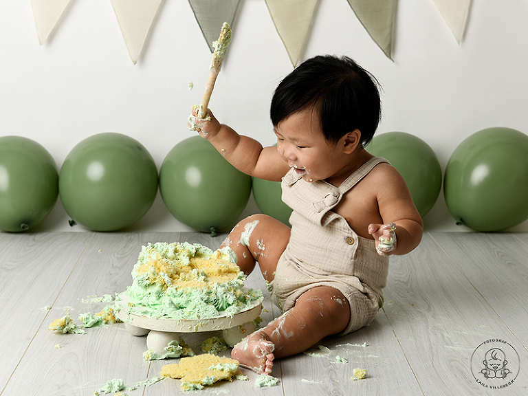 Pojke från Stockholm som kladdar med grön tårta på Smash the cake fotografering hos Fotograf Laila Villebeck